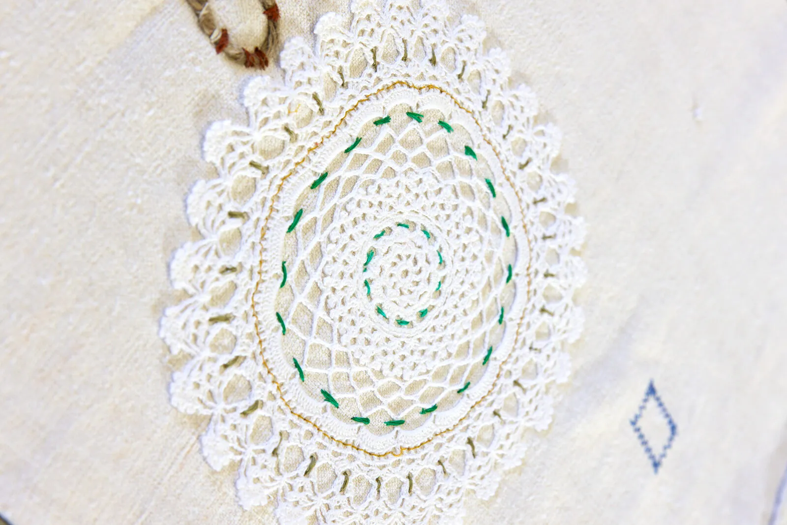 Il merletto rotondo all'uncinetto, con un filo verde che lo attraversa a spirale